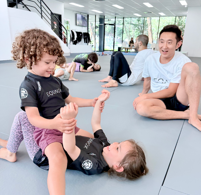 Pre-schooler students practising mount escapes, common in Brazilian Jiu-Jitsu, supervised by Equinox's head coach, James.