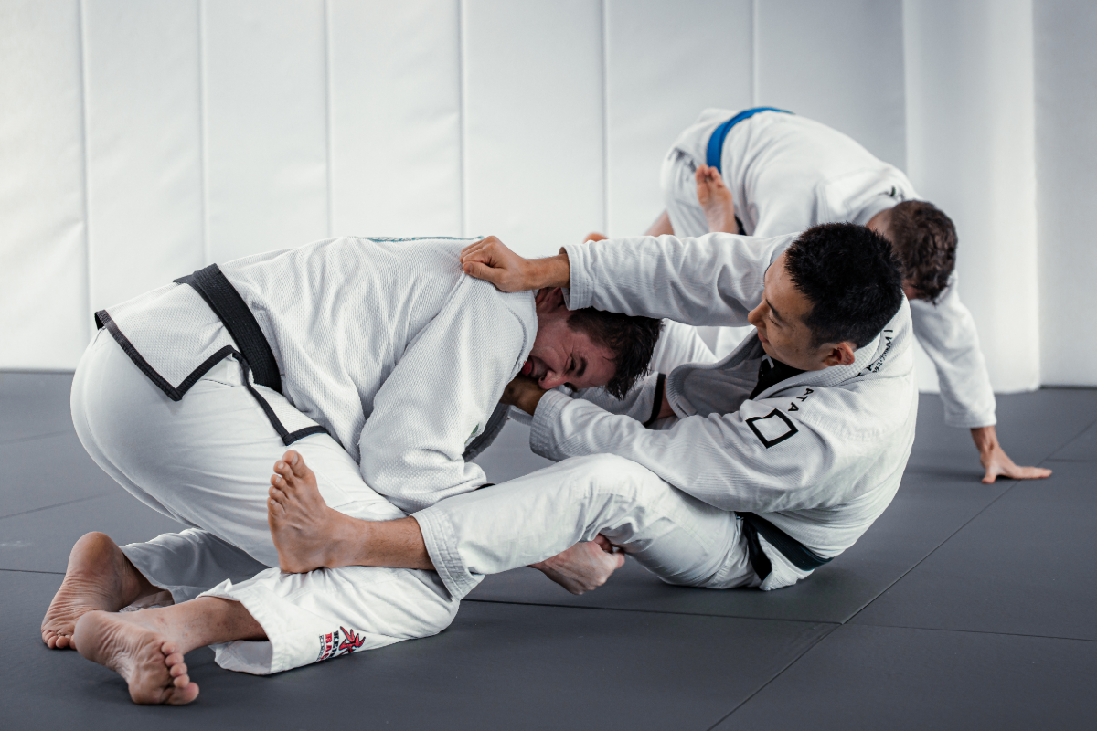 Equinox's head coach, James, performing a Brazilian Jiu-Jitsu (BJJ) cross-collar choke submission on a training partner