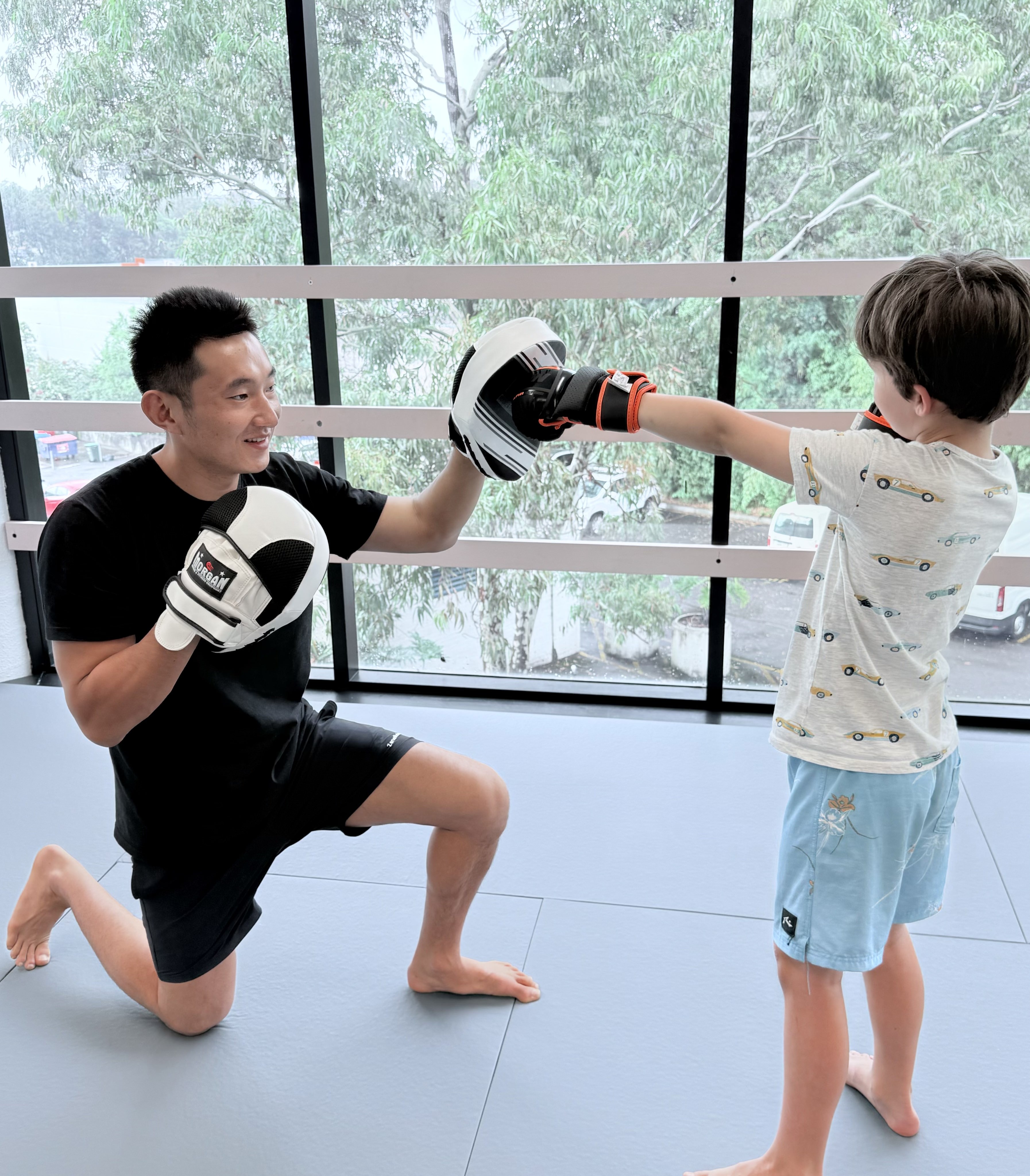 Head coach, James, holding punching pads for a young child to jab.